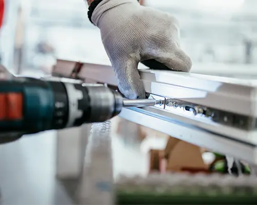 A man using a drill to attach a component to a composite piece.